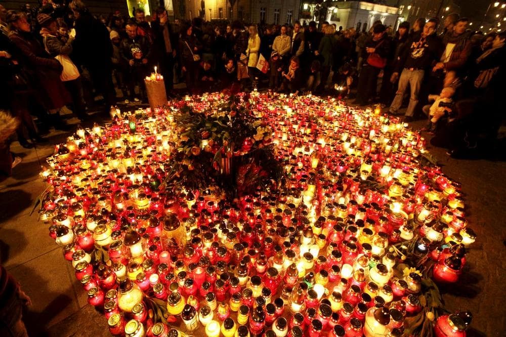 People place candles and lay flowers in front of the Presidential Palace in Warsaw, Poland, Saturday.
