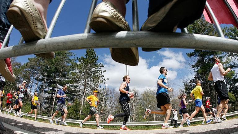 Fans stand on barricades as they cheer on runners in Wellesley during the marathon on Monday. (AP)