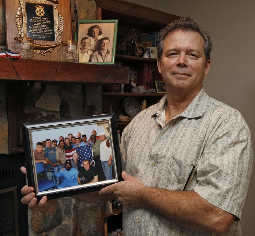 Michael Perry, 61, chief engineer of the Maersk Alabama, poses with a photo of the cargo ship&#39;s crew at his home in Riverview, Fla on Nov. 24, 2009. Perry blames Capt. Richard Phillips for the April 2009 hijacking of the ship. (AP)
