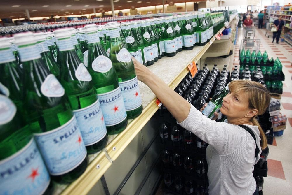 Patti Gulino, of Medford, Mass, reaches for bottled water on Sunday at a supermarket in Chelsea. (AP)