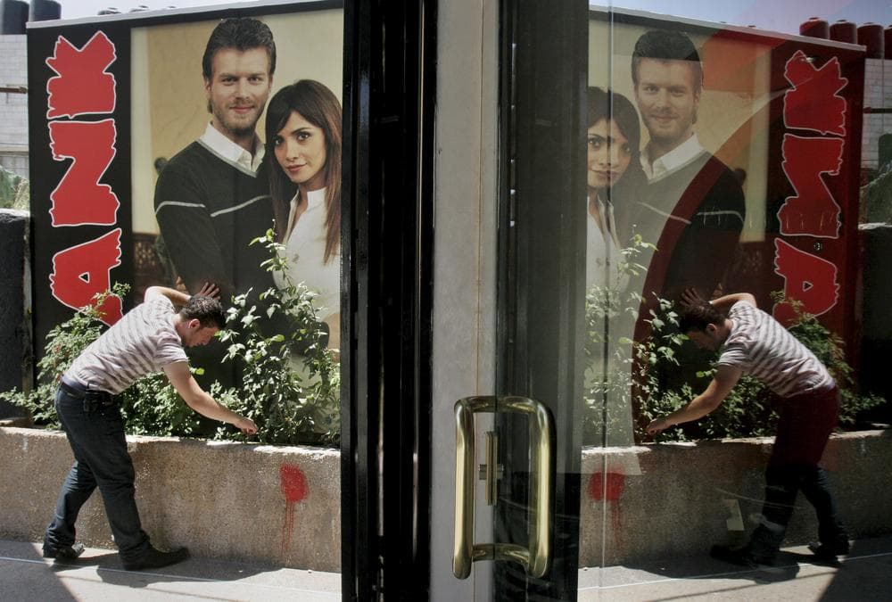 A Palestinian vendor displays a poster depicting the lead characters of Turkish TV soap opera &quot;Noor&quot; in front of his shop, in the West Bank town of Nablus, in 2008. (AP)