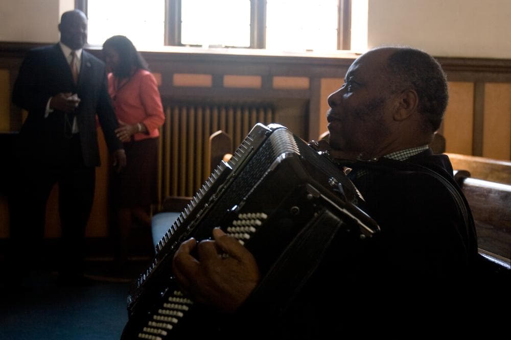 Pastor Janel Lareche, a retired minister from Haiti, practices accordion before a midday service at Philadelphie Seventh Day Aventist Church, a Haitian parish in Malden. (Jess Bidgood for WBUR)