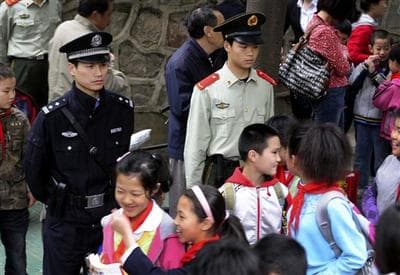A policeman and paramilitary police officer are now on watch over children as they leave a primary school as Chinese officials warned police will open fire on any future school attackers &quot;without mercy.&quot; (AP)