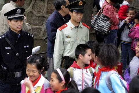 Chinese authorities watch over children as they leave a primary school in Hefei in central China&#039;s Anhui province, May 14, 2010. A string of recent assaults killed seven preschoolers and two adults last week on the outskirts of Hanzhong city. (AP)