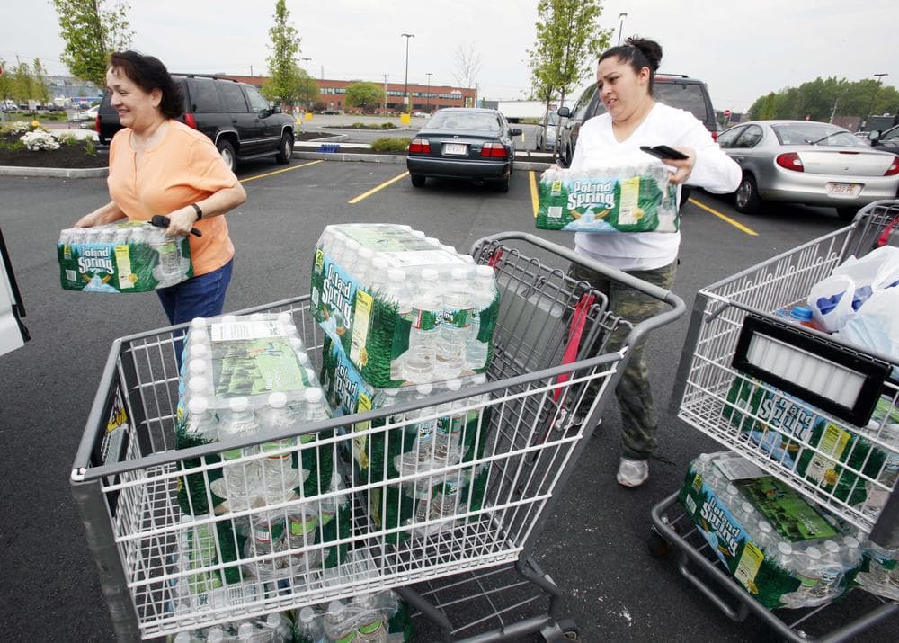 Enelcy Scott, left, and Diana Cardona load bottled water into their car outside a supermarket in Chelsea on Sunday. (AP)
