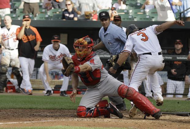 Baltimore's Cesar Izturis scores the winning run on a single by Nick Markakis as Boston catcher Jason Varitek waits for the throw at the plate during the 11th inning of the game on Sunday in Baltimore. The Orioles won 4-3. (AP)