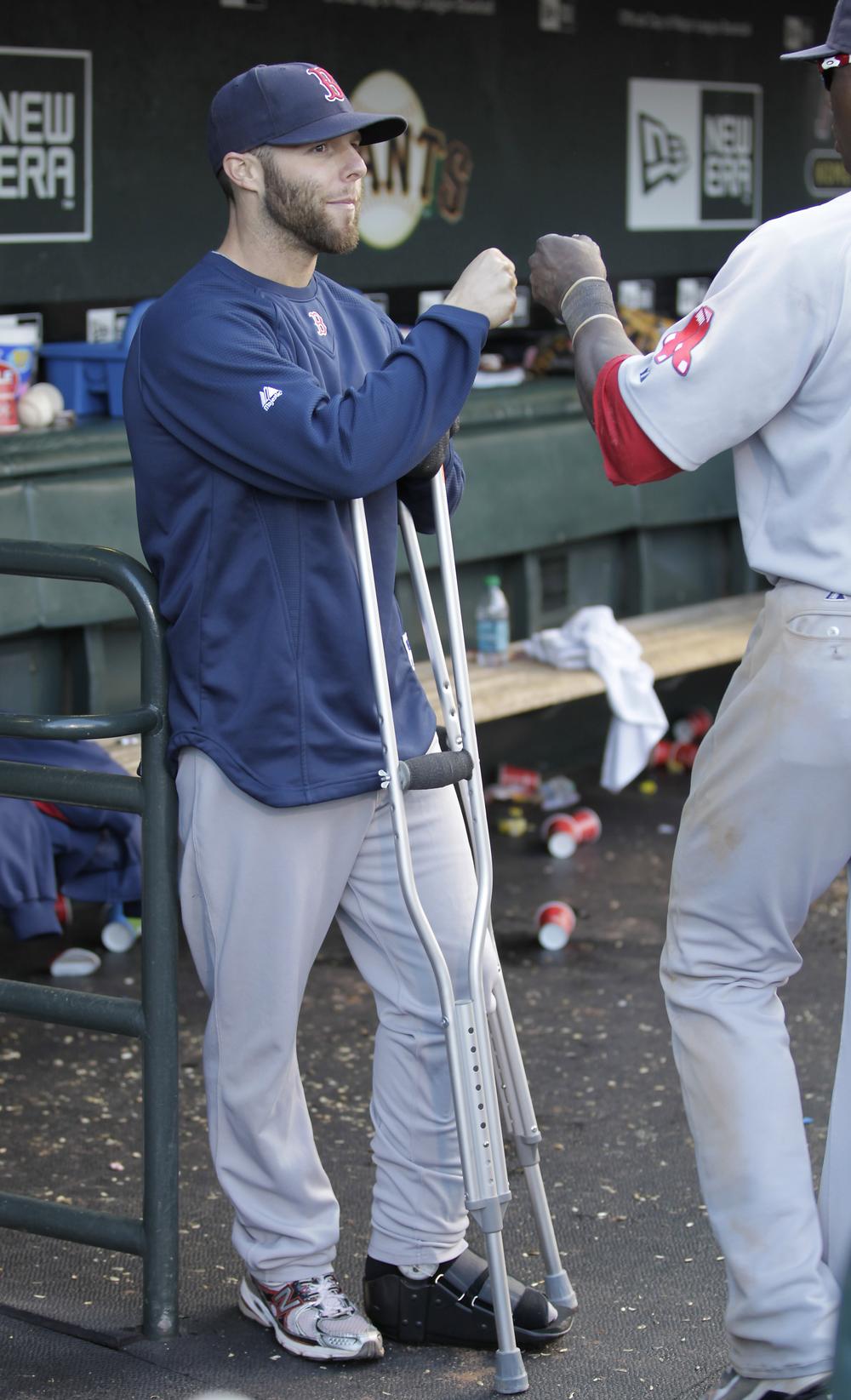 Dustin Pedroia, left, is seen in the dugout on crutches congratulating teammates after a 4-2 victory against the San Francisco Giants on Saturday. (AP)
