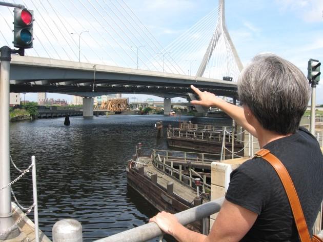 Kate Bowditch, of the Charles River Watershed Association, points to where the river meets Boston Harbor. She hopes public swimming will be possible here some day. (Sacha Pfeiffer/WBUR)
