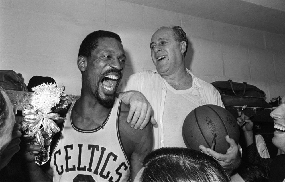Celtics center Bill Russell, left, holds a corsage sent to the locker room as he and coach Red Auerbach celebrate after defeating the Lakers to win their eighth straight NBA championship in 1966. (AP)
