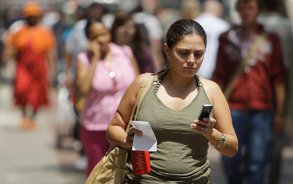 A woman sends text messages while walking through downtown Chicago. (AP)