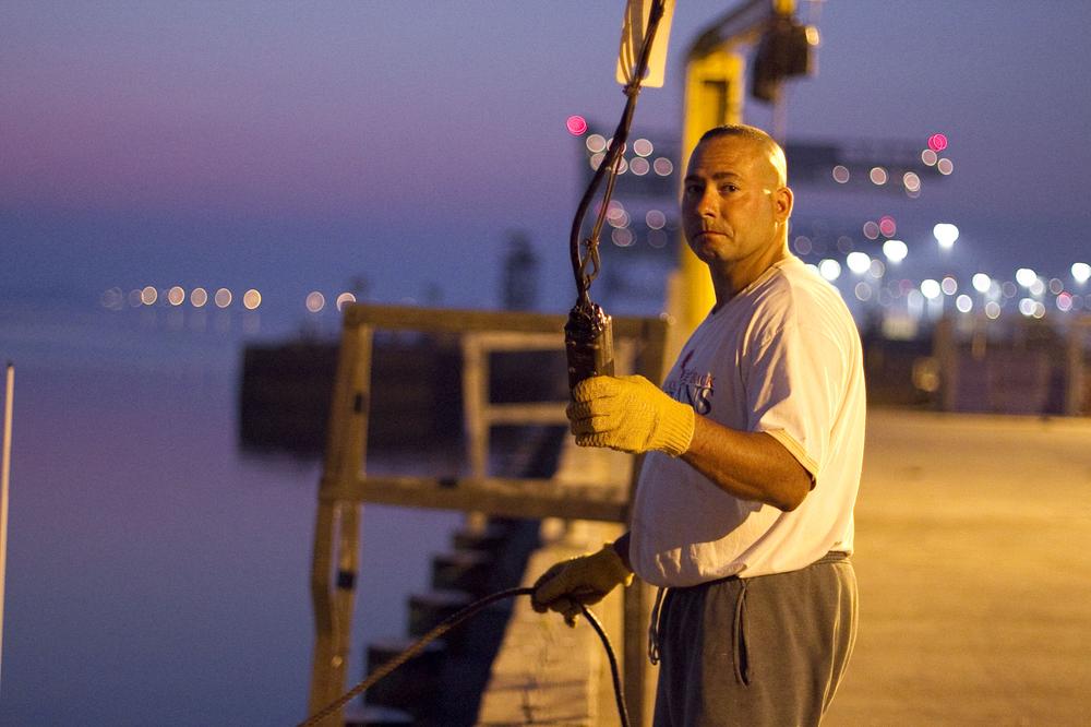 Paul Cabral, a laid-off elevator mechanic, helps Skip Ryan on his lobster boat to earn extra money. (Jess Bidgood for WBUR)