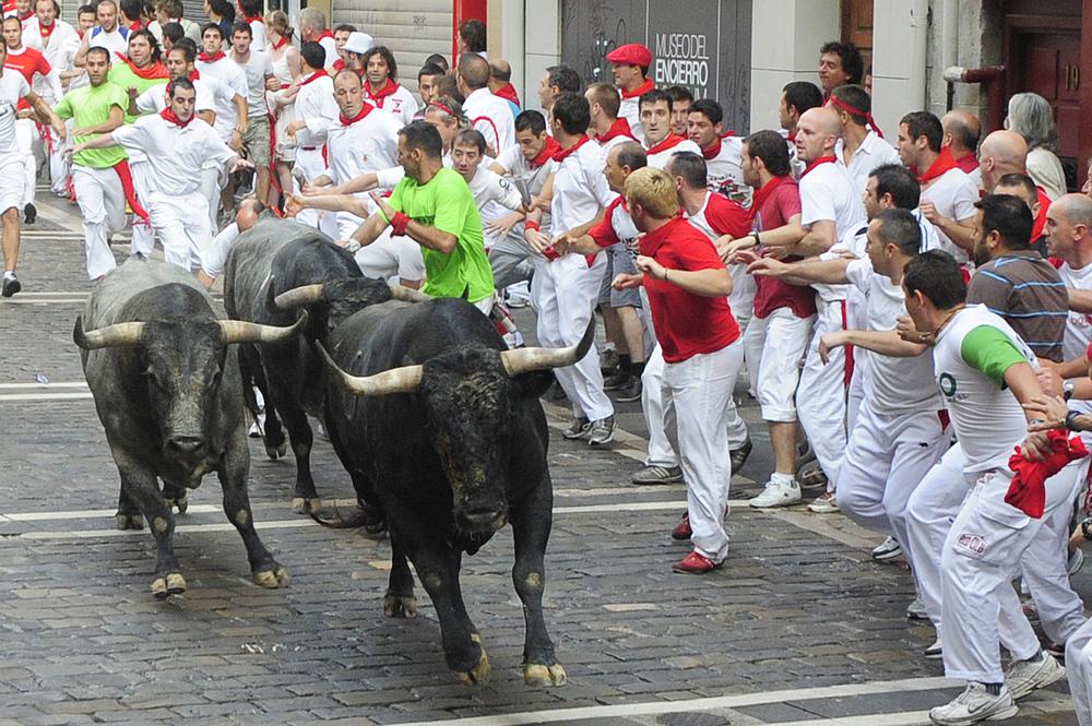 Revelers run next to Miura ranch fighting bulls during the fifth day of the running of the bulls at the San Fermin fiesta in Pamplona, Spain, Sunday. (AP Photo/Manu Fernandez)