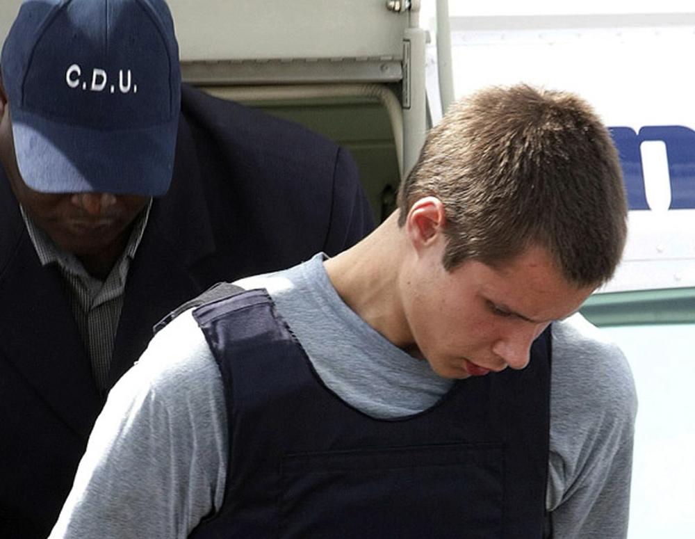 Colton Harris-Moore exits a plane handcuffed as he is escorted by police upon arrival to Nassau, Bahamas. (AP)