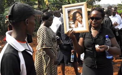 A relative carries a photograph during a burial ceremony for Alice Kyalimpa, one of dozens of people killed in the Sunday bomb blast in Wakiso, west of Uganda&#039;s capital city Kampala. (AP)