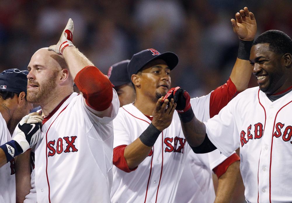 Kevin Youkilis, left, celebrates with teammates Eric Patterson, center, and David Ortiz, right, after hitting a sacrifice fly that allowed the winning run to score in the eleventh inning against the Rangers, Saturday, in Boston.  (AP Photo/Michael Dwyer)