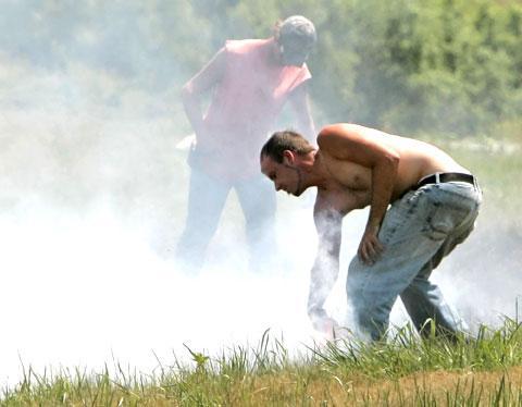 Members of a road maintenance crew try to control a grass fire near Lincoln, Neb., using their shirts and boots, July 17, 2007. Dry conditions and 99 degree temperatures contributed to the fire. (AP)