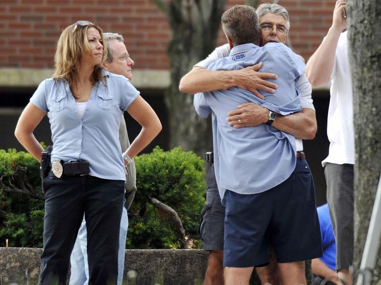 Workers comfort each other after evacuating the Hartford Distributors building during the shootings. (AP)