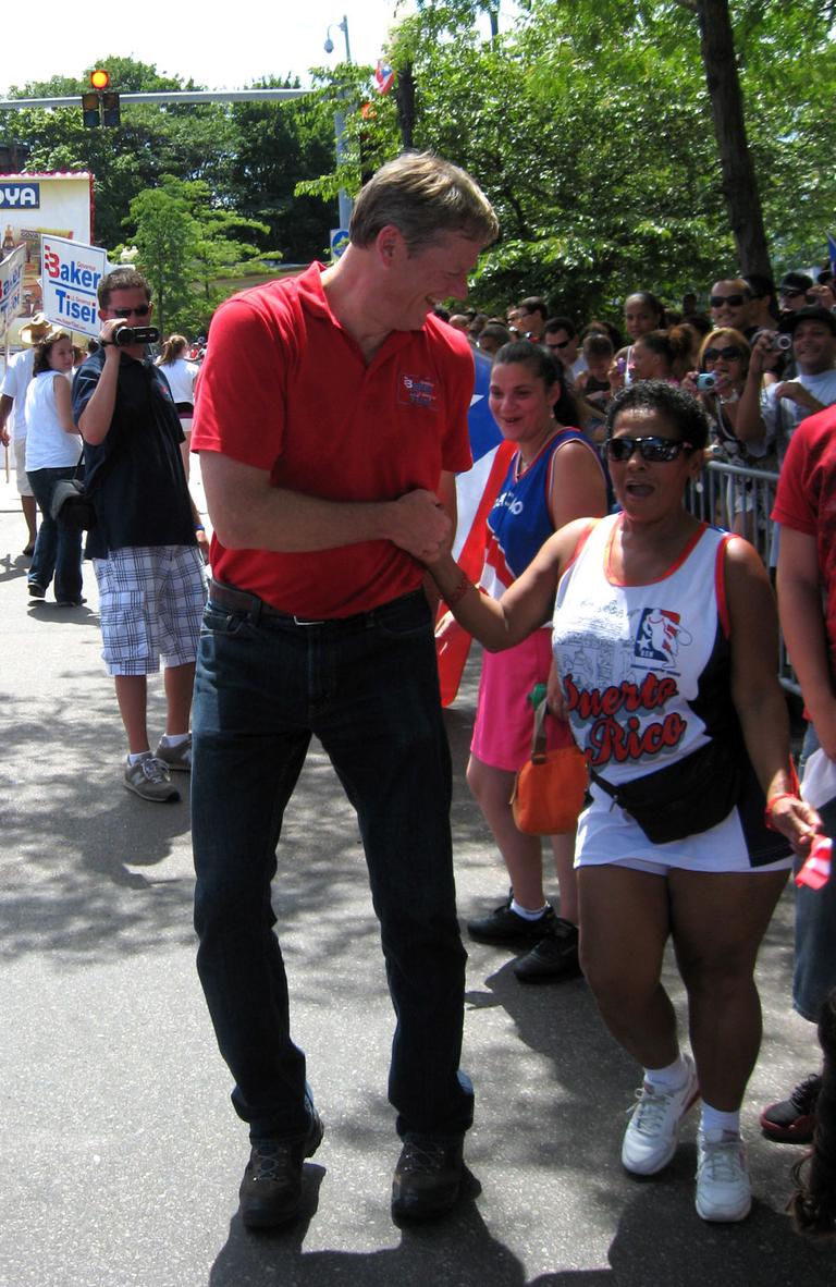 Baker dances with a crowd member during a campaign stop at Boston&#39;s Puerto Rican Festival Parade. (David Boeri/WBUR)
