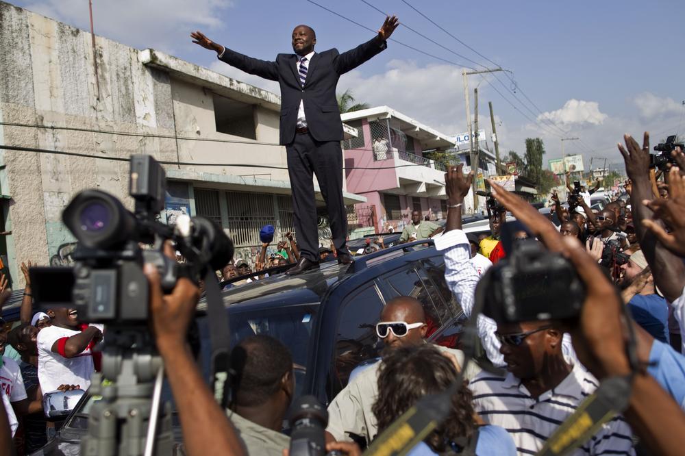 Haitian-born singer Wyclef Jean, center, greets supporters from the top of a vehicle after submitting the paperwork to run for president of Haiti in Port-au-Prince, Haiti.  (AP)