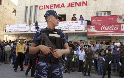 A police officer stands guard as Palestinians gather for the opening of Cinema Jenin in the Palestinian West Bank city of Jenin. (AP)