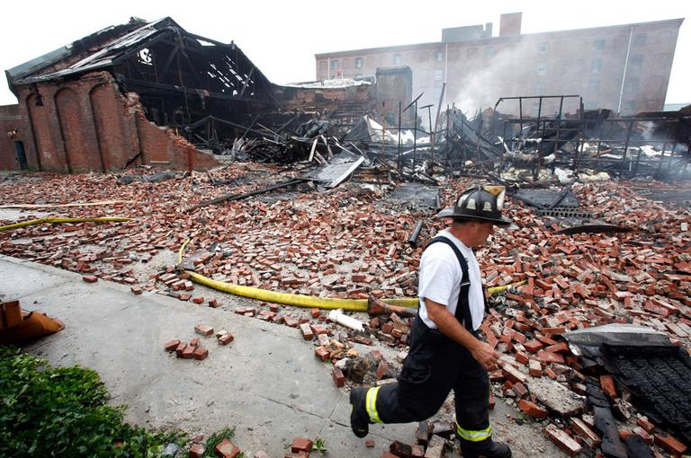 A firefighter walks past the scene of a nine-alarm fire at a warehouse in the Roxbury neighborhood of Boston on Sunday. (AP)