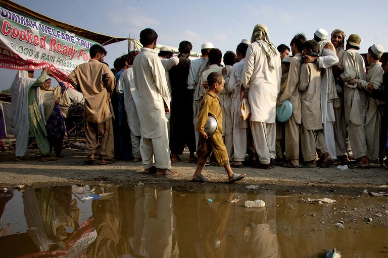 Pakistani flood-affected people stand in a queue to get relief food at a food distribution center on the outskirts of Nowshera, Pakistan on Monday. (AP)