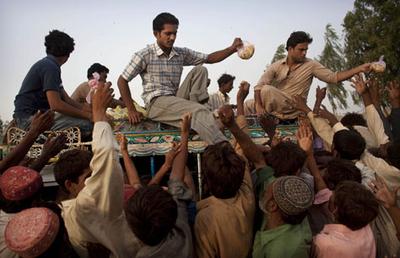 Pakistanis displaced by flooding reach for food aid thrown by a volunteer during a distribution outside a temporary camp operated by the Pakistan Army, in southern Pakistan on Thursday. (AP)
