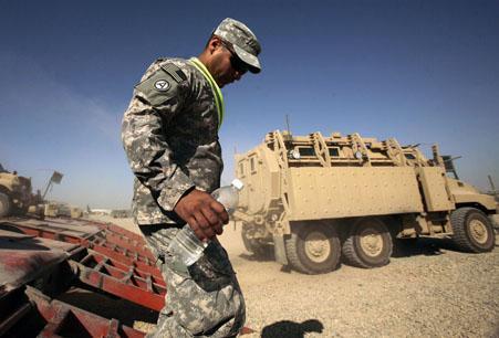 U.S. Army Sgt. Norberto Rodriguez disembarks from a flat bed truck while loading armored vehicles set to leave Iraq. (AP)