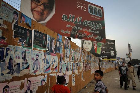 Afghans walk past by posters of the parliamentary candidates in Kabul, Afghanistan Monday, Sept. 13, 2010. (AP Photo)