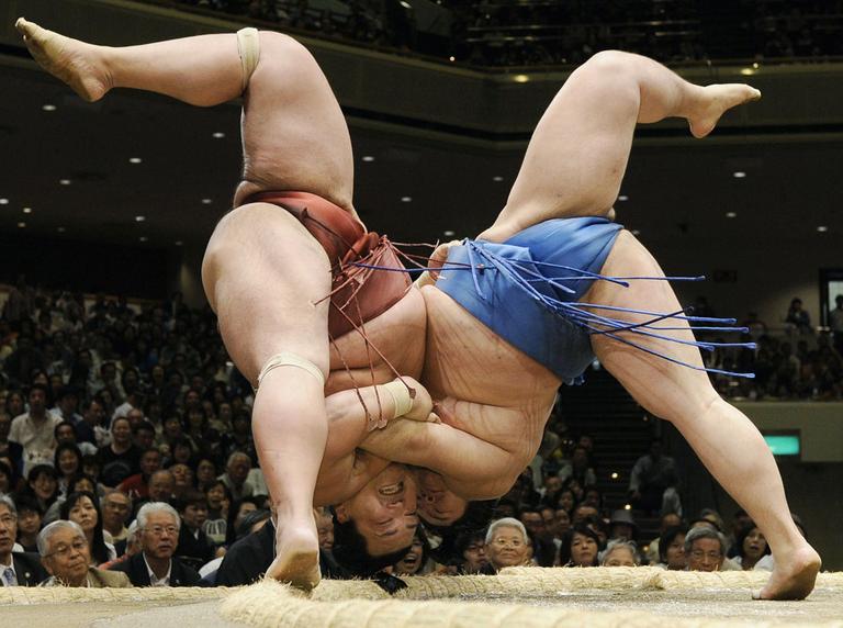 Sumo wrestlers Tosayutaka, right, and Toyohibiki fall to the dirt during their bout in the grand summer tournament at Tokyo's Ryogoku Kokugikan sumo arena on Sunday May 9, 2010. (AP)