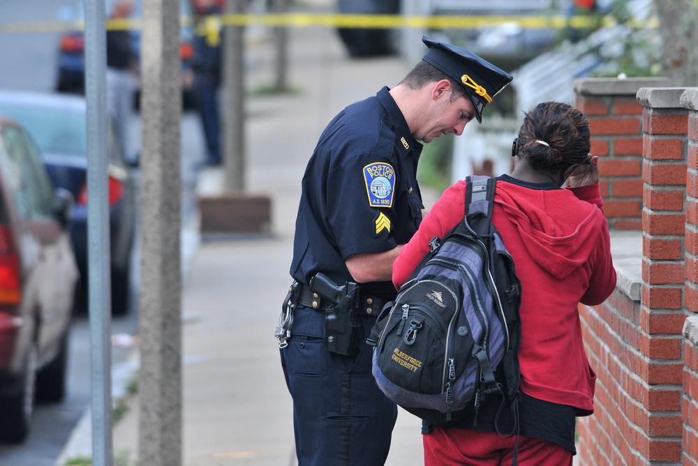 A Boston police officer speaks to a Mattapan neighbor on Tuesday, near the scene of an early morning shooting in which five people, including a toddler, were shot. (AP)
