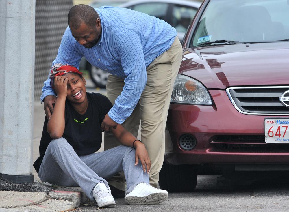 A man comforts a grieving woman near the scene of a shooting in the Mattapan neighborhood of Boston on Tuesday. (AP)