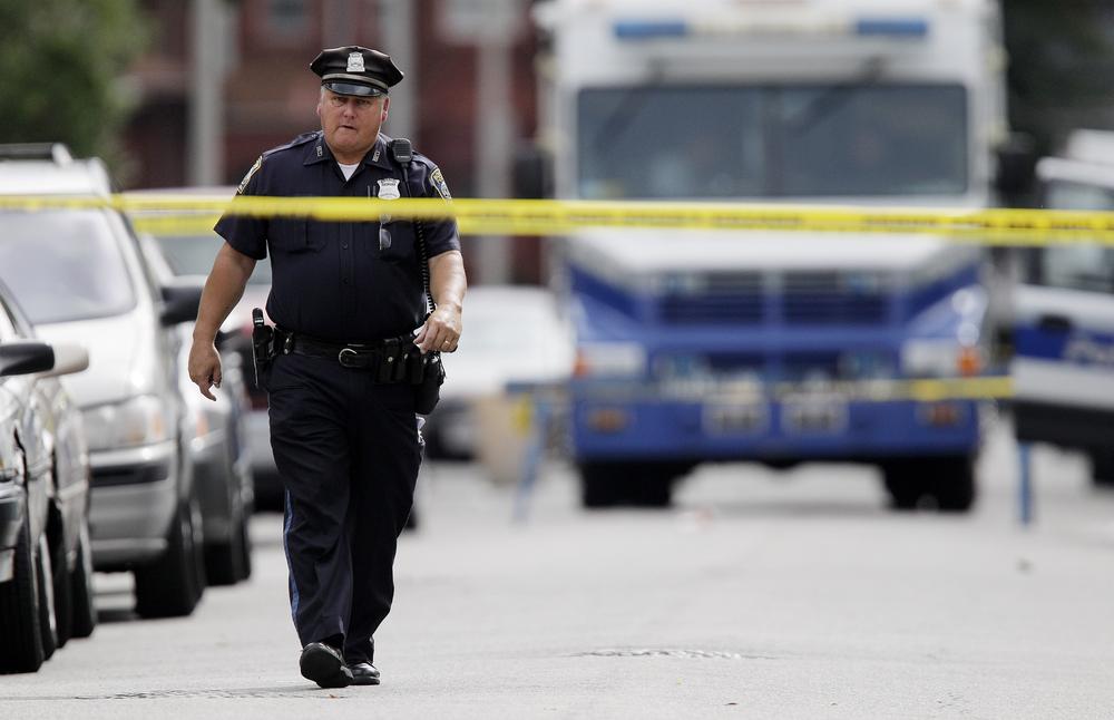 A police officer walks up Woolson Street in the Mattapan neighborhood of Boston, near a house where five people were shot, including a toddler, on Tuesday. (AP)