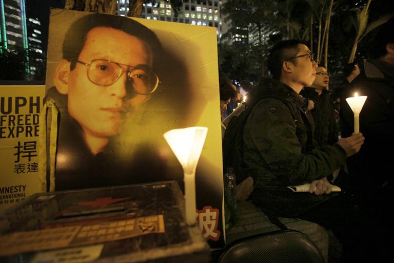 Pro-democracy protesters hold a candle light vigil supporting jailed dissident Liu Xiaobo, shown on a poster, in Hong Kong. (AP)
