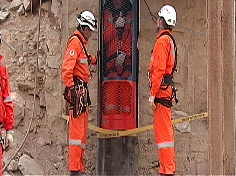 This image, taken from a video and released by the government of Chile on Monday, shows rescue workers looking on as a colleague gives a thumb up from inside the rescue capsule. (AP)