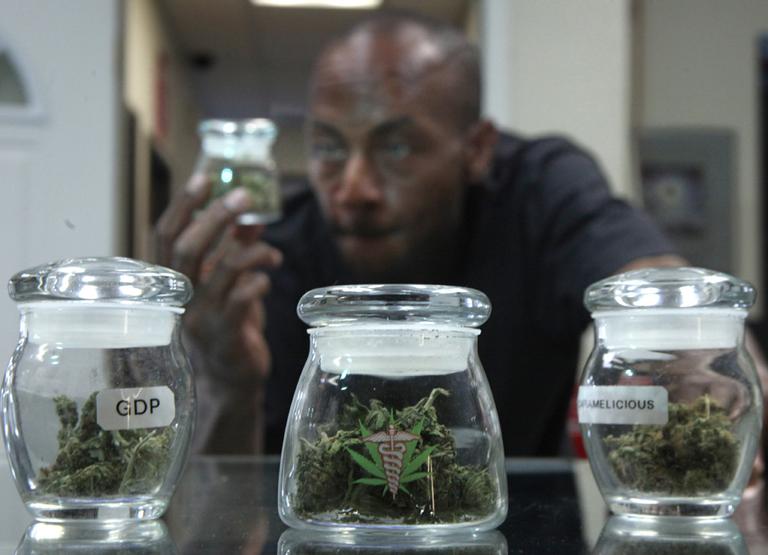 Medical marijuana patient Ezekiel Muses, who uses the drug for back pain, checks out a jar of medical marijuana at a legal dispensary. (AP)