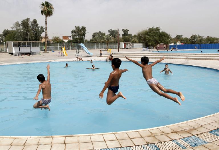 Boys leap into a public swimming pool in Baghdad in June. (AP)