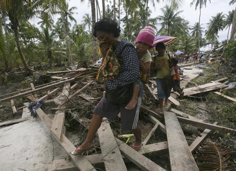 Tsunami survivors walk through their tsunami-devastated village. (AP)