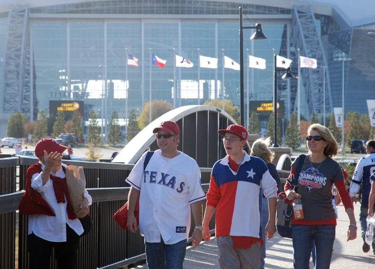 Rangers fans walk to the baseball stadium with Cowboys Stadium in their wake. (Karen Given/WBUR)