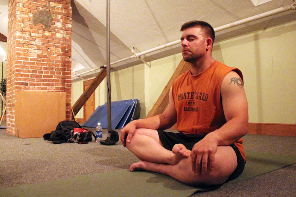In the dim light of the attic at the Easton YMCA, Marine Corps veteran Derek Adameic practices yoga. (Andrew Phelps/WBUR)