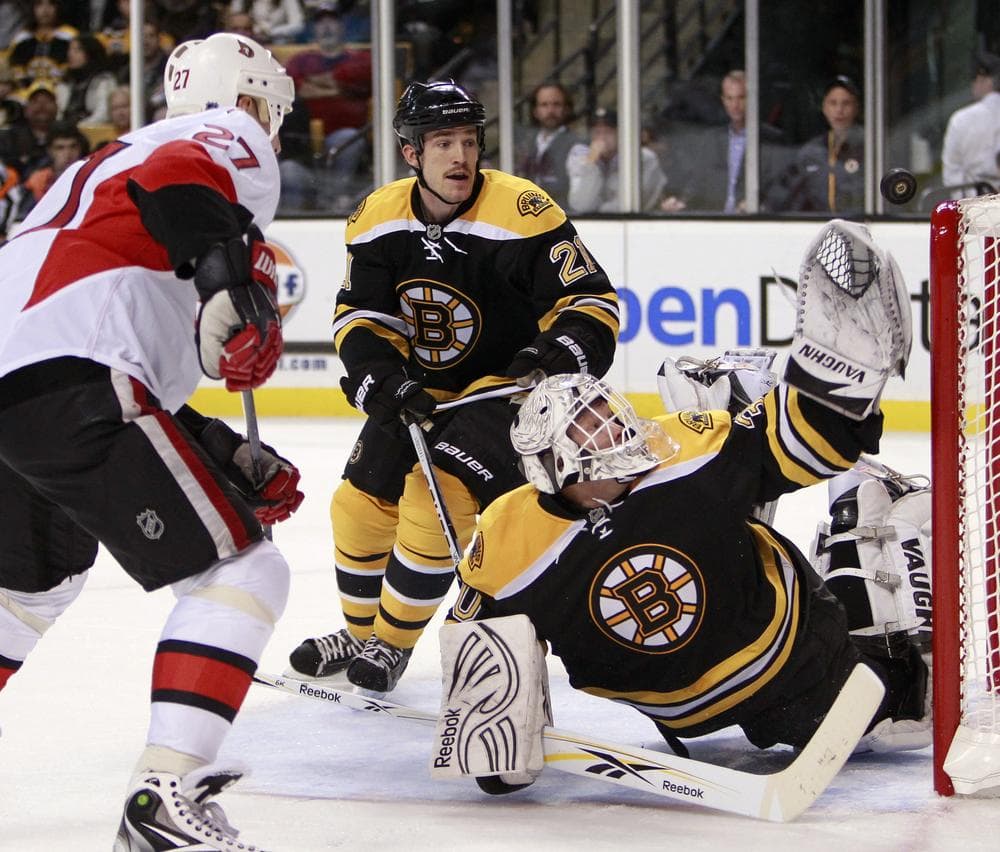 Bruins'  Tim Thomas, right, reaches for the puck as  Andrew Ference (21) and Ottawa Senators' Alex Kovalev (27), of Russia, look on in the third period, Saturday, in Boston.  (AP Photo/ Michael Dwyer)