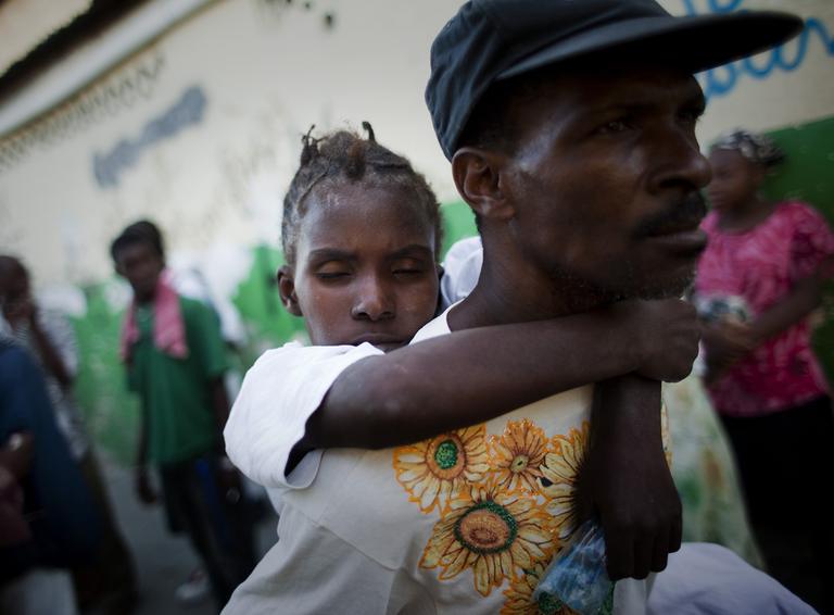 A young woman suffering cholera symptoms is carried by a relative to St. Catherine hospital, run by Doctors Without Borders, in the Cite Soleil slum in Port-au-Prince, Haiti, Friday Nov. 19, 2010. (AP)