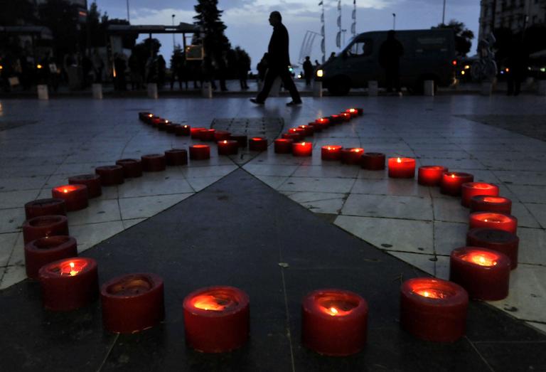 A man walks behind candles form a ribbon touring event at the city of Thessaloniki, northern Greece, Wednesday.