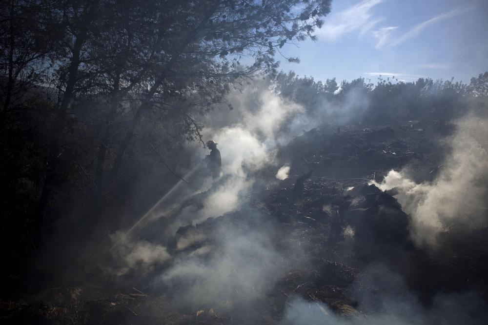 An Israeli firefighter attempts to extinguish a blaze in the youth village (boarding school) of Yemin Orde, near the northern city of Haifa, Israel, Sunday. (AP)