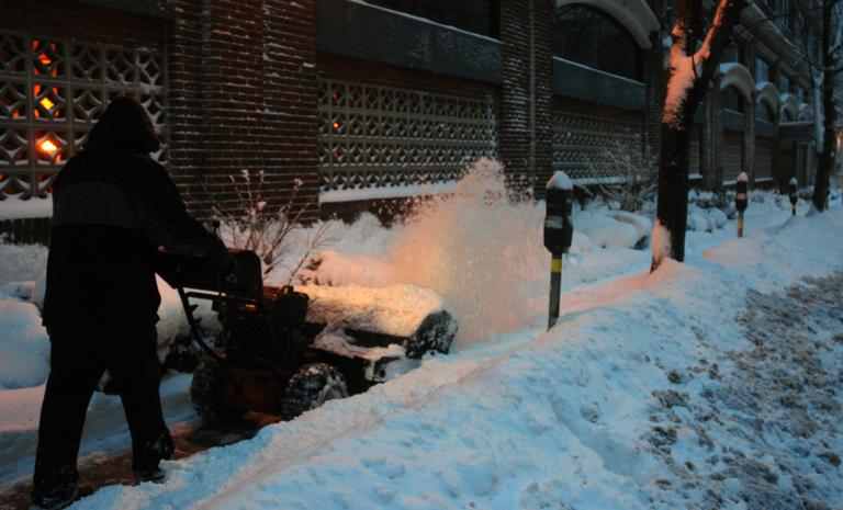A man clears a sidewalk in front of an apartment building in Brookline. (Jeremy Bernfeld for WBUR)