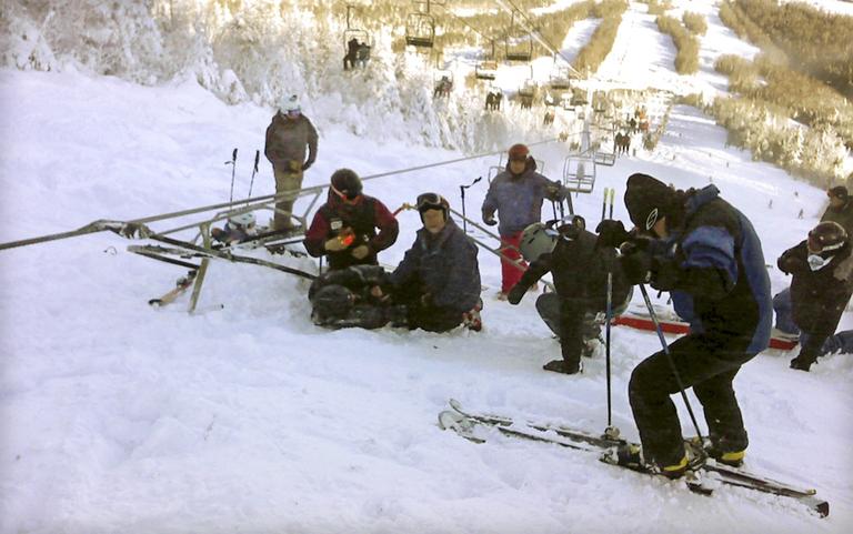 Skiers attending a skier who fell onto the slope after a chair lift derailed on the state's tallest ski mountain at the Sugarloaf resort in Carrabassett Valley, Maine, Tuesday, Dec. 28, 2010. (AP)