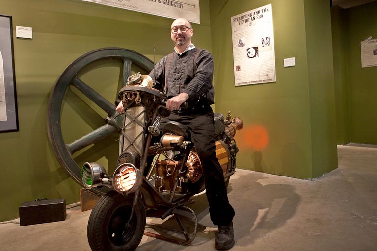 Bruce Rosenbaum, owner of Steampuffin and ModVic, sits on top of a steampunked scooter.