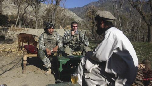 U.S. servicemen drink tea with an Afghan man near the Pakistani border in Kunar province, eastern Afghanistan, Dec 20, 2010. (AP)