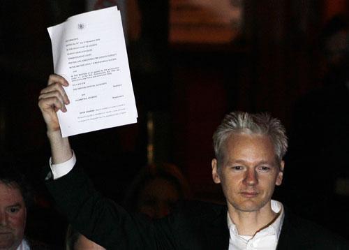 WikiLeaks founder Julian Assange holds up a court document after he was released on bail, outside the High Court, London, Dec. 16, 2010. (AP)