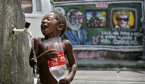 A boy takes a bath at a public faucet in the Complexo de Alemao slum in Rio de Janeiro, 2008. (AP)